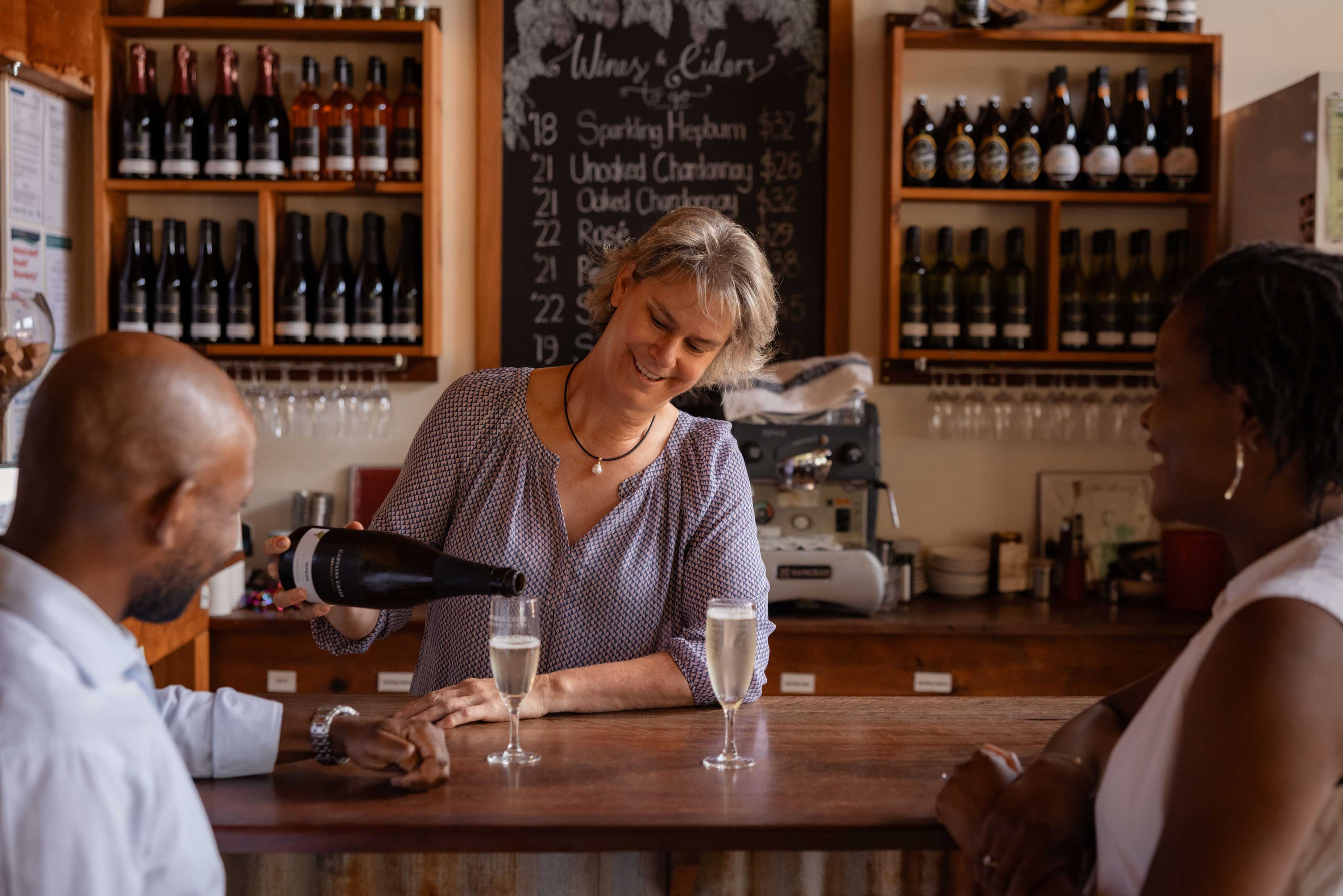 A bartender pours two glasses of wine for guests.